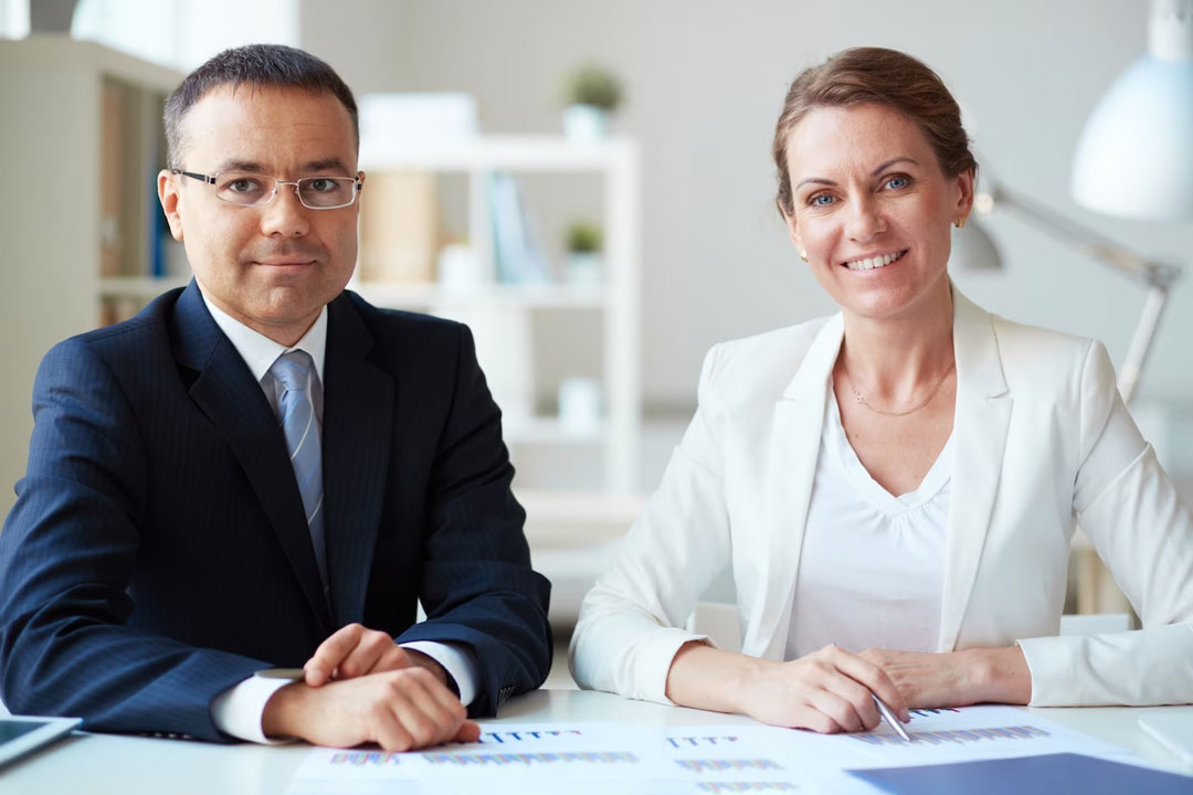 Casal de executivos de meia idade, um homem e uma mulher, analisando dados contábeis do escritório.
