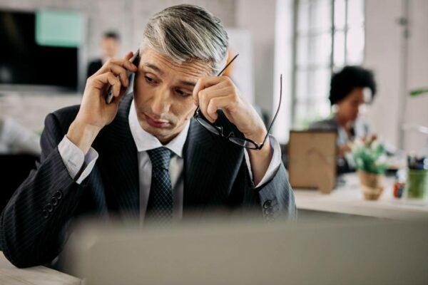 empresario-falando-no-celular-enquanto-esta-sentado-na-mesa-no-escritorio